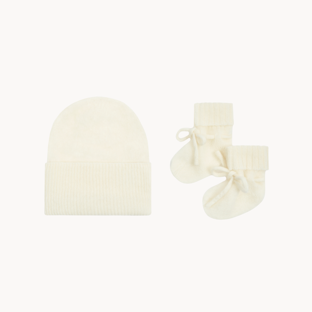 Cream-colored baby hat and socks set on a white background