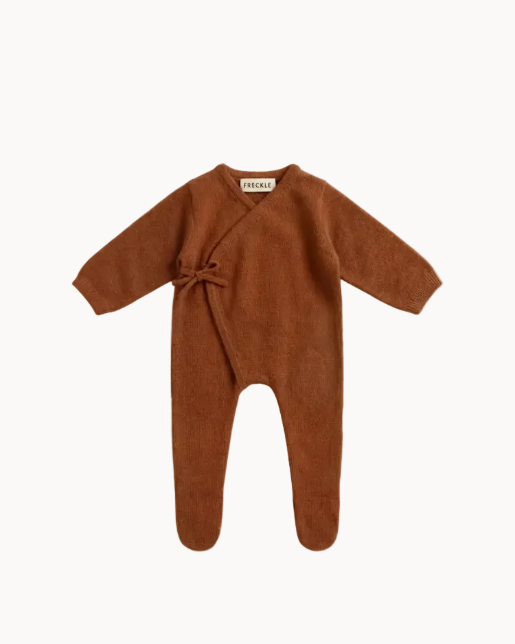 Brown baby onesie with a tie on a beige background