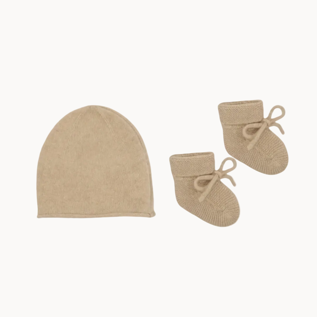Beige baby hat and booties set on a white background