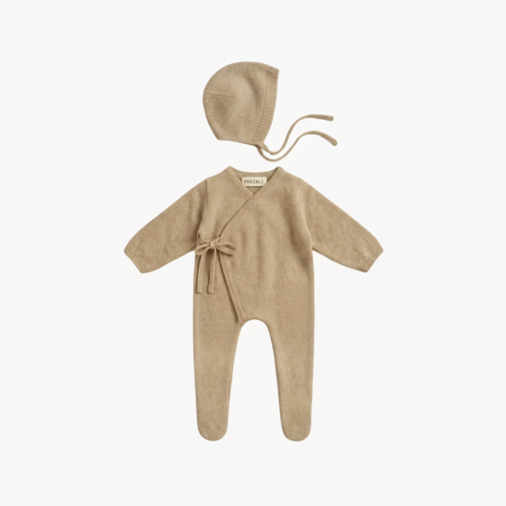 Beige baby outfit set with romper, bonnet, and socks on a white background