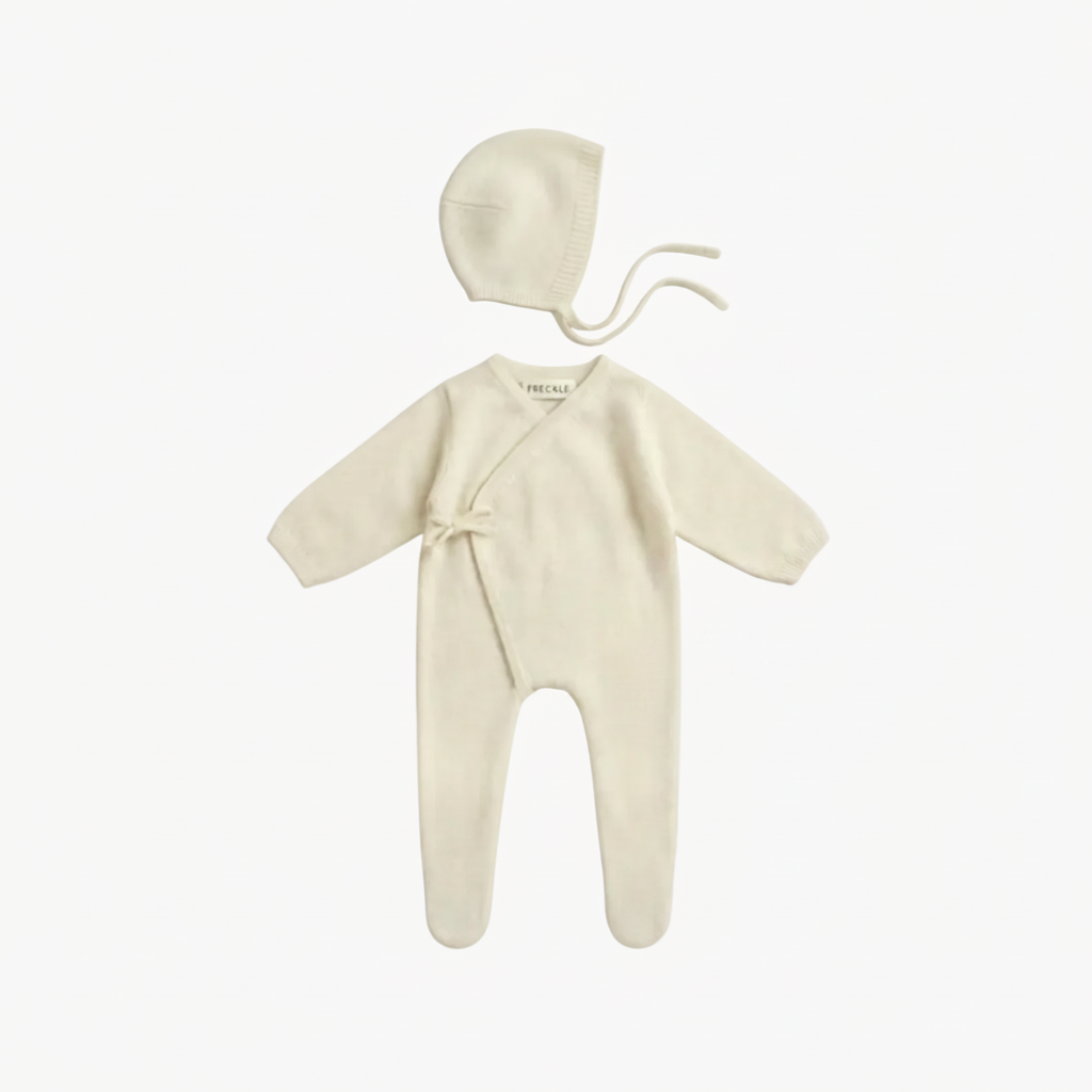 Baby outfit set with onesie, bonnet, and socks on a white background