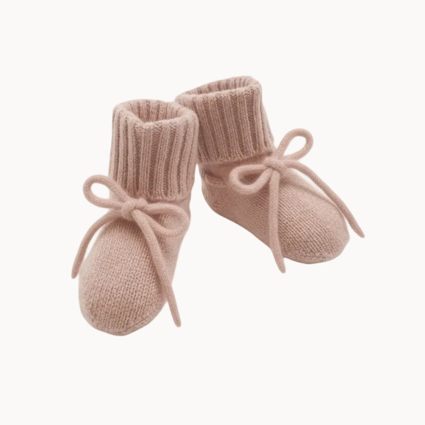 Pair of pink knitted baby booties with ribbons on a white background