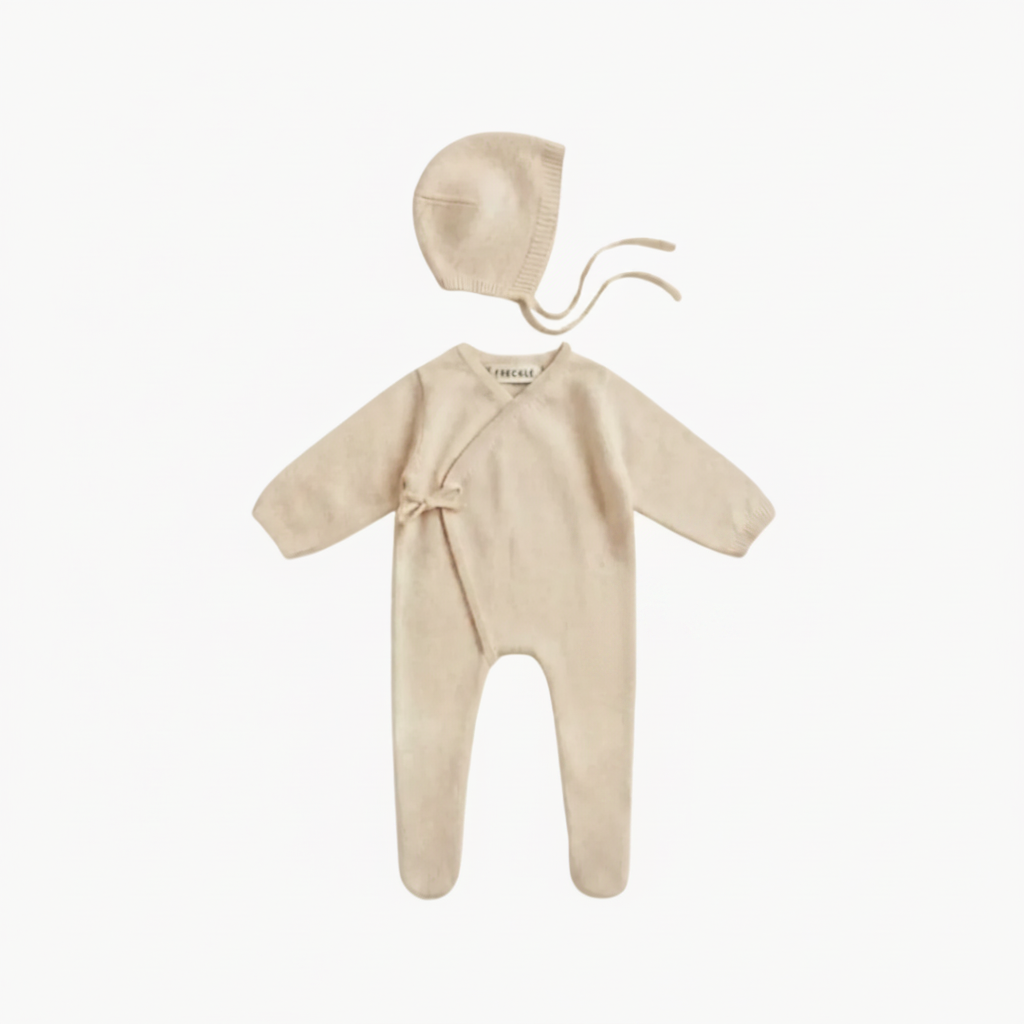 Baby outfit set with onesie, bonnet, and socks on a white background